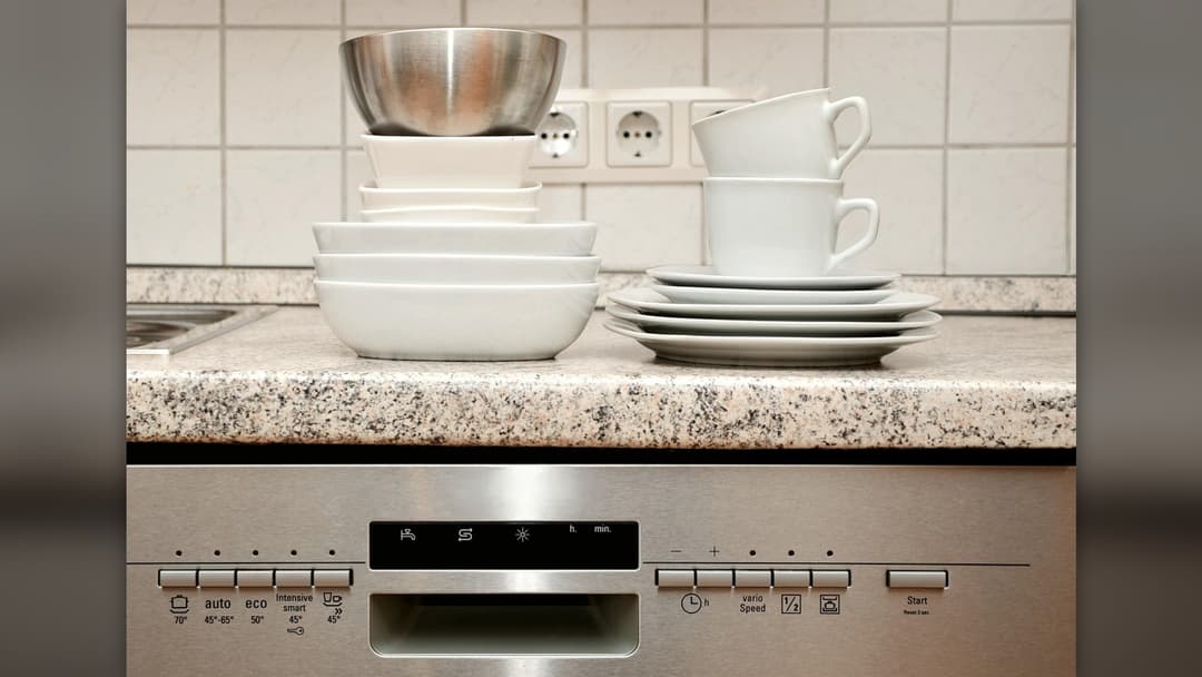 Open kitchen dishwasher rack filled with clean plates and glasses