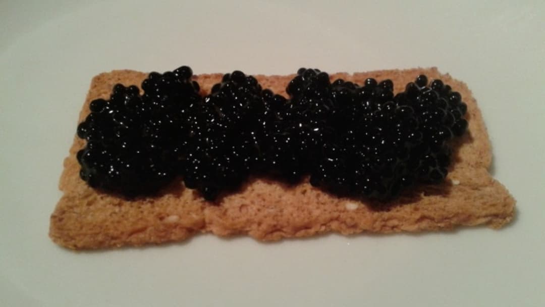 Black caviar served on crisp toast points with garnishes