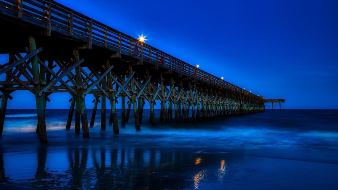 Sunset view of the Atlantic Ocean pier and sandy coastline in Myrtle Beach South Carolina