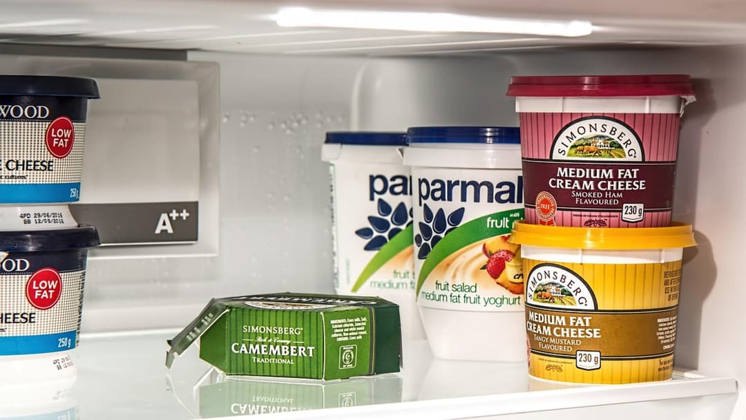 Open household refrigerator stocked with food containers on glass shelves