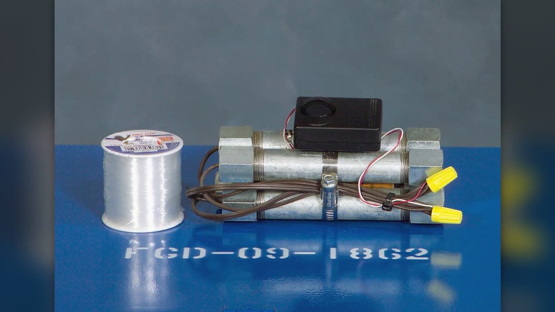 Metal pipe bomb assembly with wiring and battery pack on an inspection table