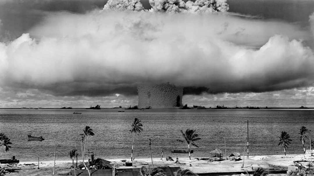 Massive nuclear test mushroom cloud rising over the ocean horizon