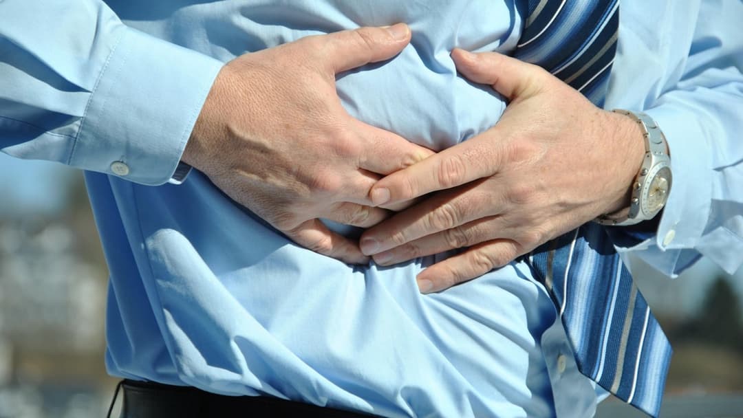Landscape photograph of a person clutching their stomach in acute discomfort