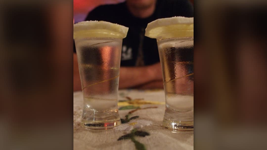 Chilled glass shot of vodka served with a fresh slice of lemon