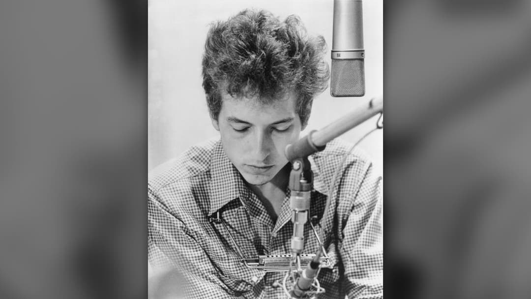 Bob Dylan holding acoustic guitar in a 1963 publicity photo