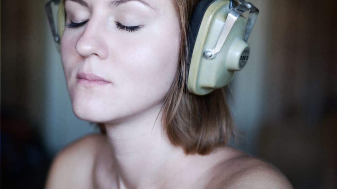 Close-up of a listener with eyes closed deeply absorbed in an emotional song through headphones