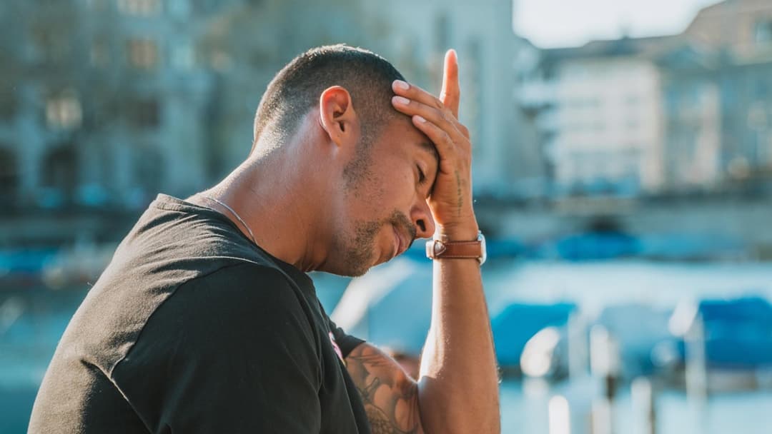 Landscape photograph of a stressed man holding his head in worry