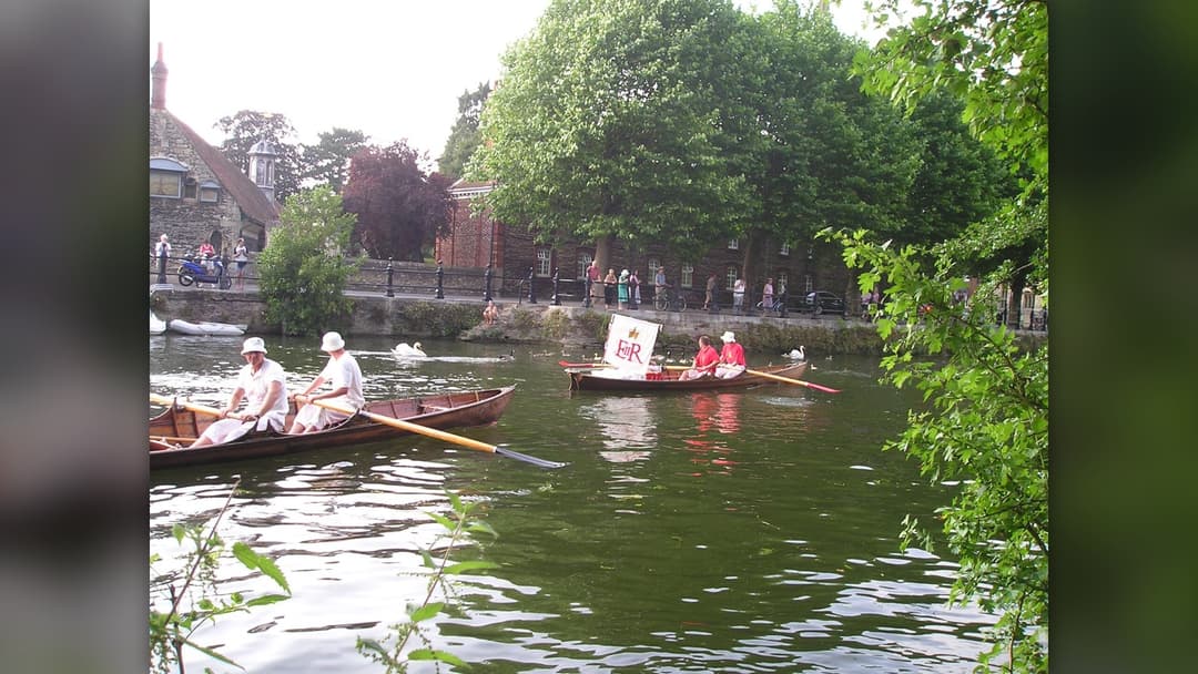 Swan uppers in traditional scarlet uniforms on the River Thames