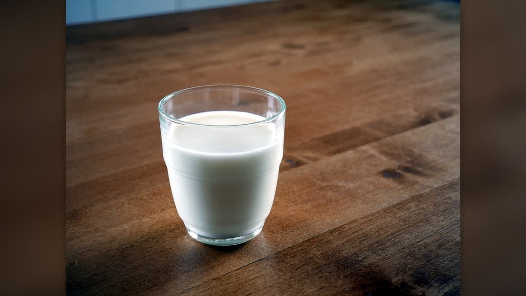 Clear glass filled with fresh whole cold milk
