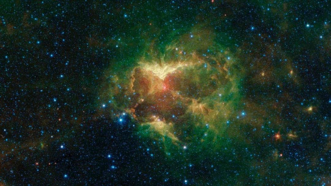 NASA Spitzer Space Telescope infrared image of the Jack-o'-Lantern Nebula glowing orange and green