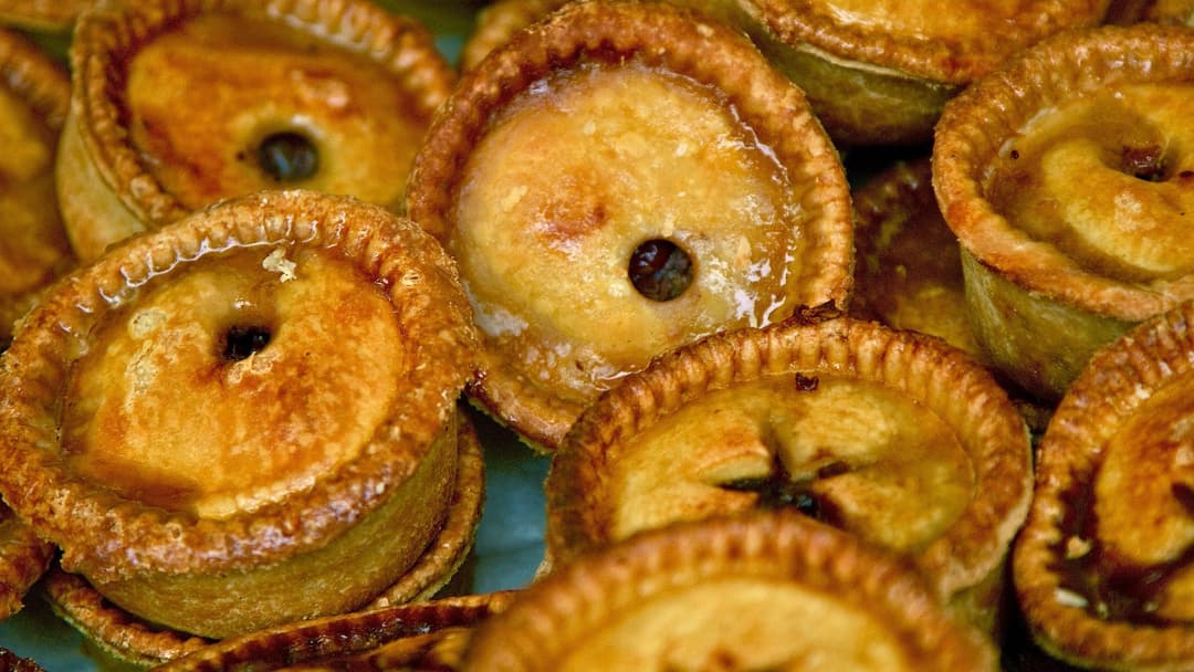 Packed batch of whole golden-crusted British pork pies lined up side by side