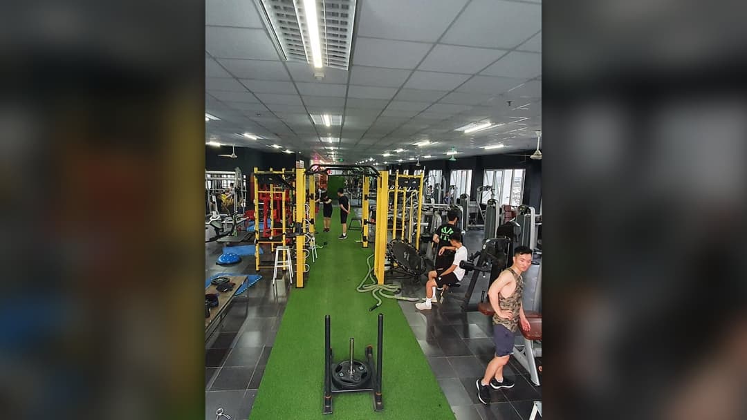 People working out in a modern fitness gym with equipment and weights.
