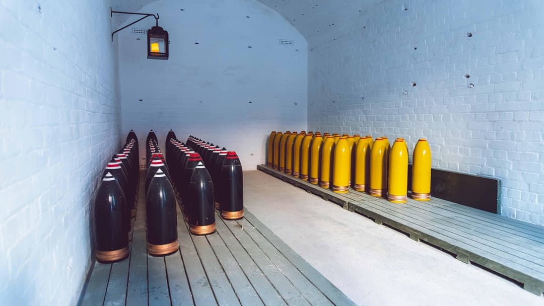Rows of heavy military artillery shells stacked inside a munitions depot