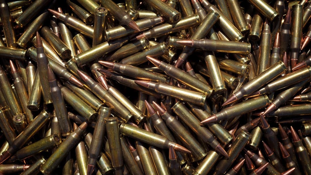 Pile of loose brass-cased live ammunition rounds and cartridges