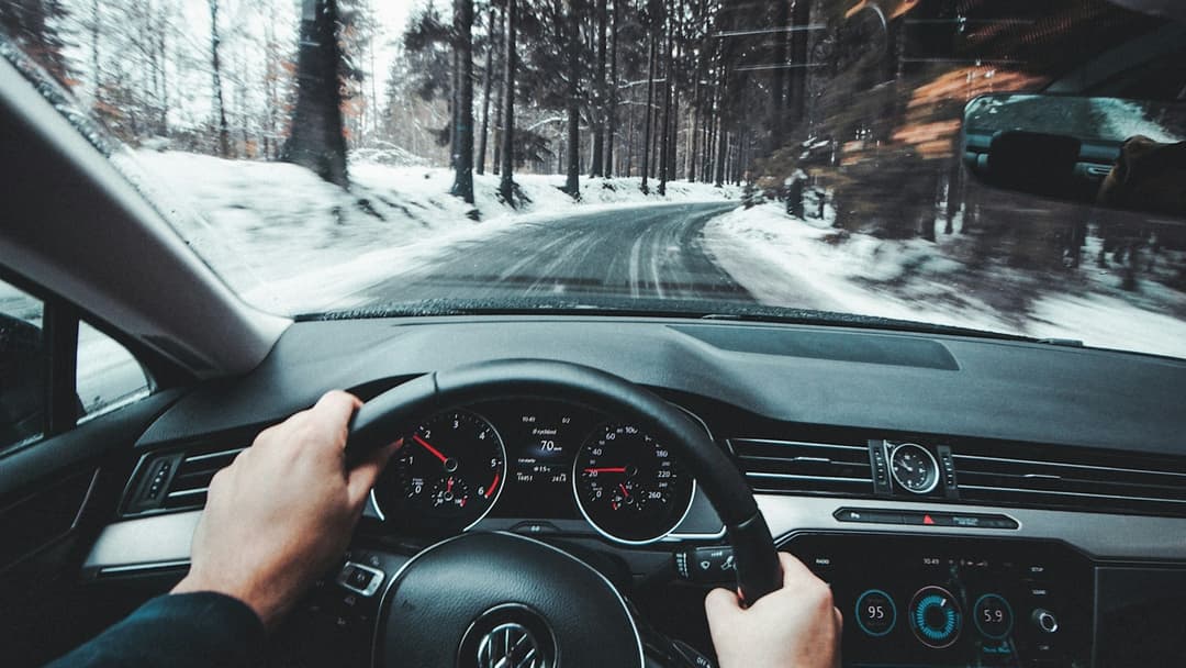Driver behind the steering wheel during a daily road commute with the dashboard display illuminated