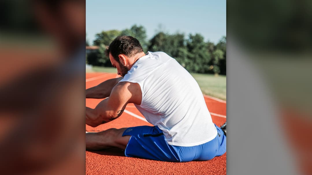 Athlete doing pre-workout mobility and warmup stretching in a gym.