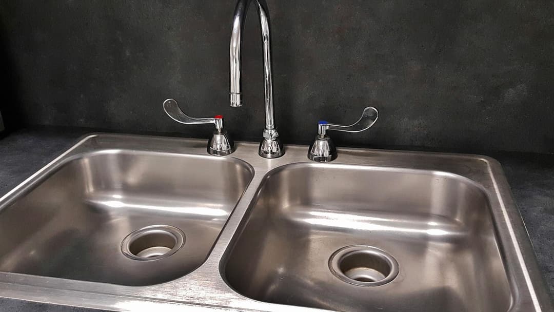 Stainless steel kitchen sink basin and drain filled with standing water