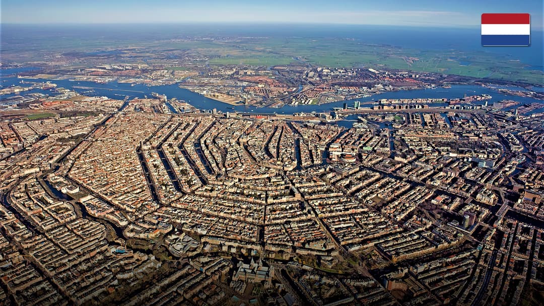 Tree-lined historic canals and arched brick bridges in central Amsterdam, Netherlands.