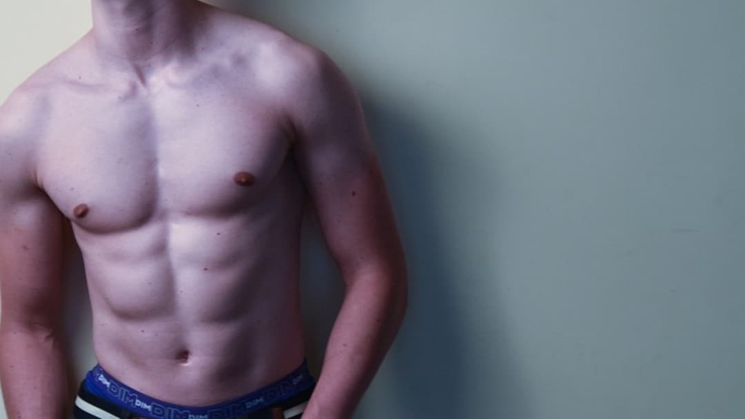 Young male model with sculpted chest, defined abdominal contour, and sharp jawline