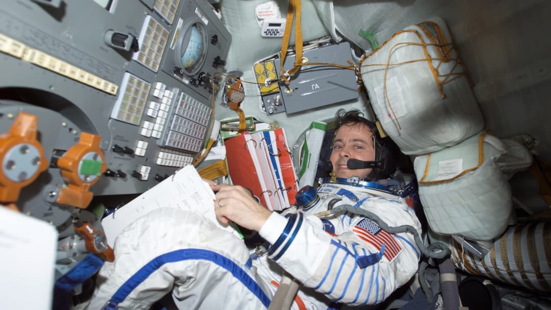 NASA astronaut Daniel Bursch wearing a spacesuit fitted inside the compact Soyuz spacecraft cabin