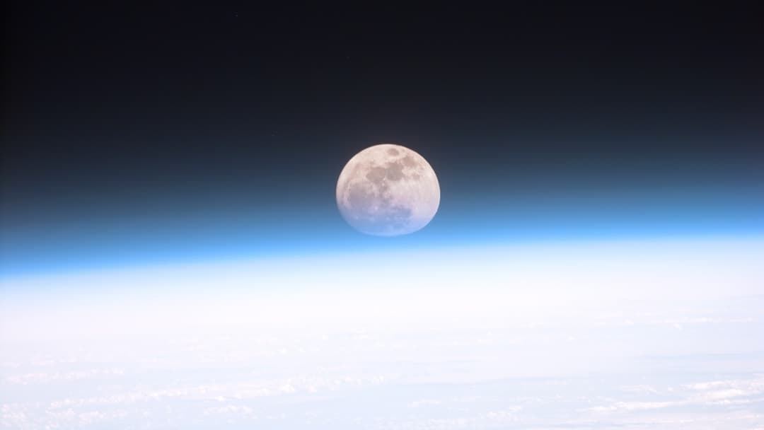 Full Moon viewed above the blue limb of Earth's atmosphere from orbit