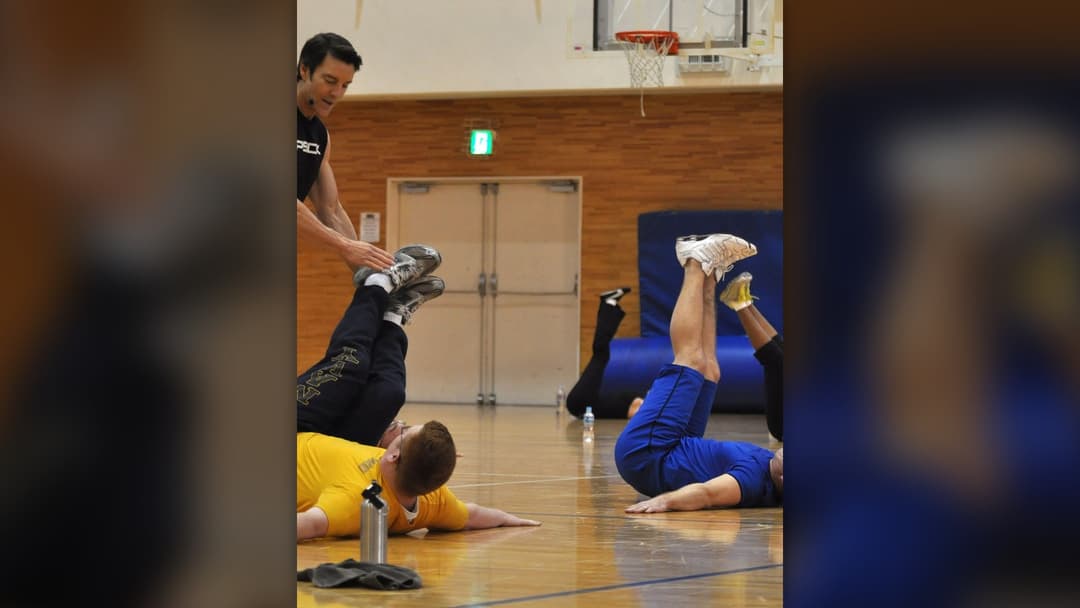 Fitness coach instructing naval personnel on proper abdominal exercise execution.