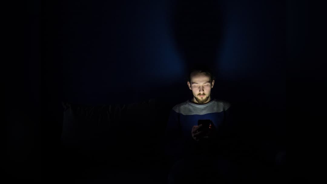 Glowing smartphone screen illuminating a dark room at night