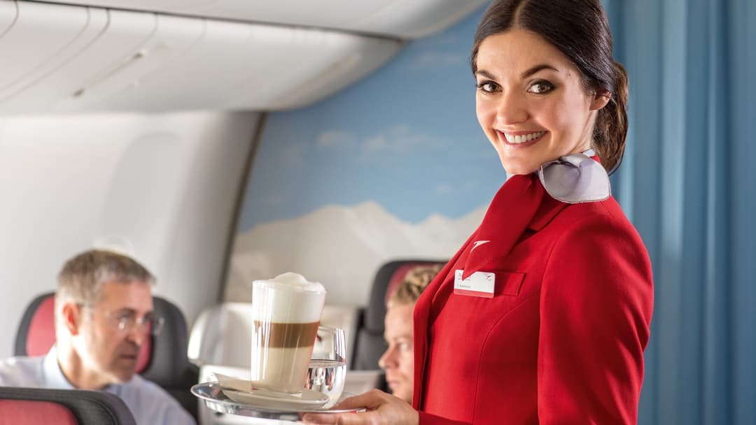 Flight attendant pouring morning coffee and serving refreshments to passengers in an airplane cabin