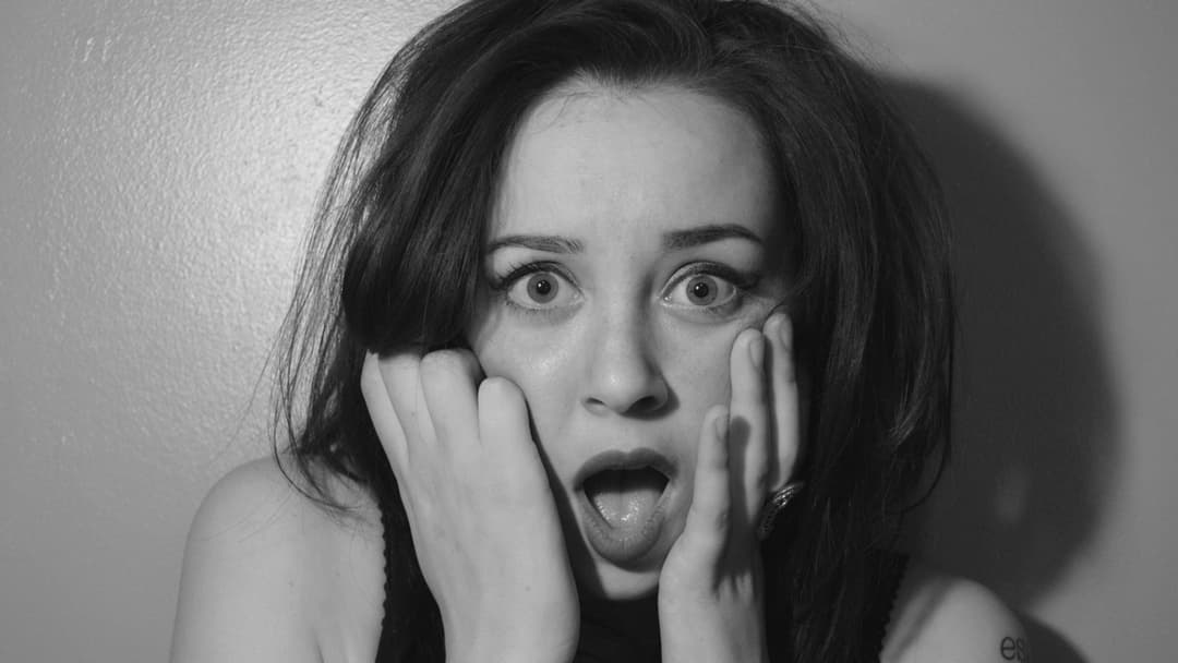 Landscape photograph of a shocked woman holding her hands to her face in fear
