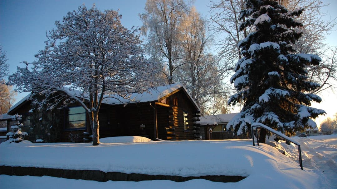 Log cabin nestled in deep crisp winter snow in Anchorage, Alaska