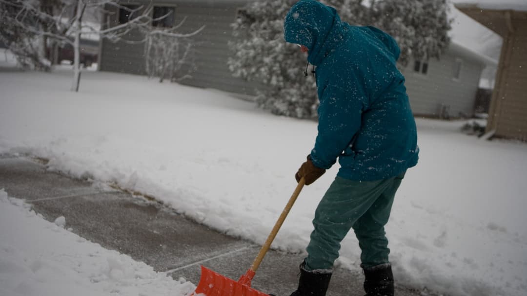 Resident shoveling heavy snow off a sidewalk in Fargo, North Dakota