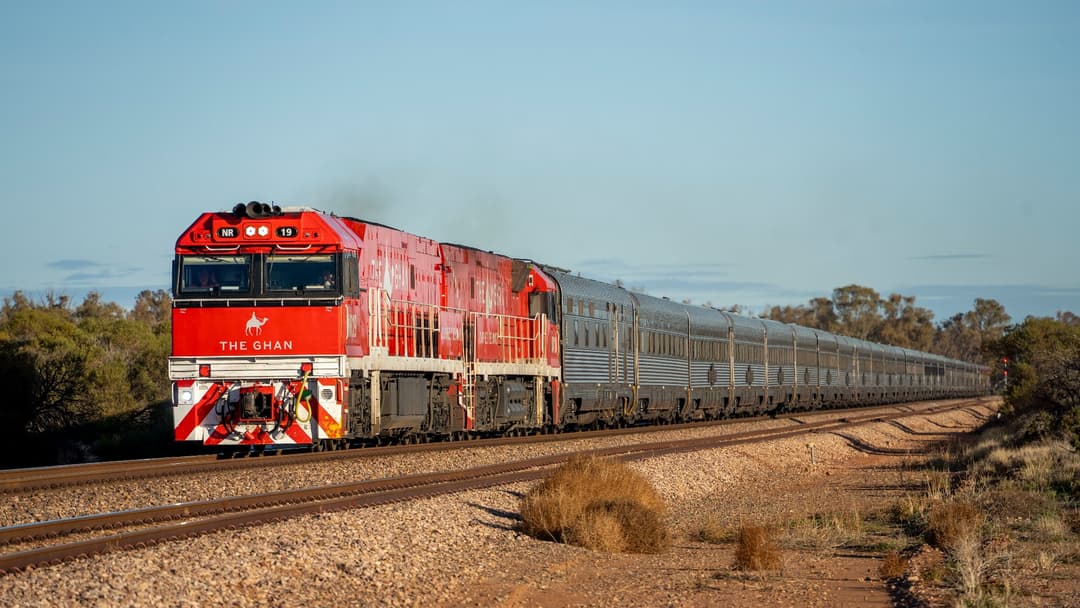The Ghan passenger train hauled by a red locomotive through the South Australian outback.