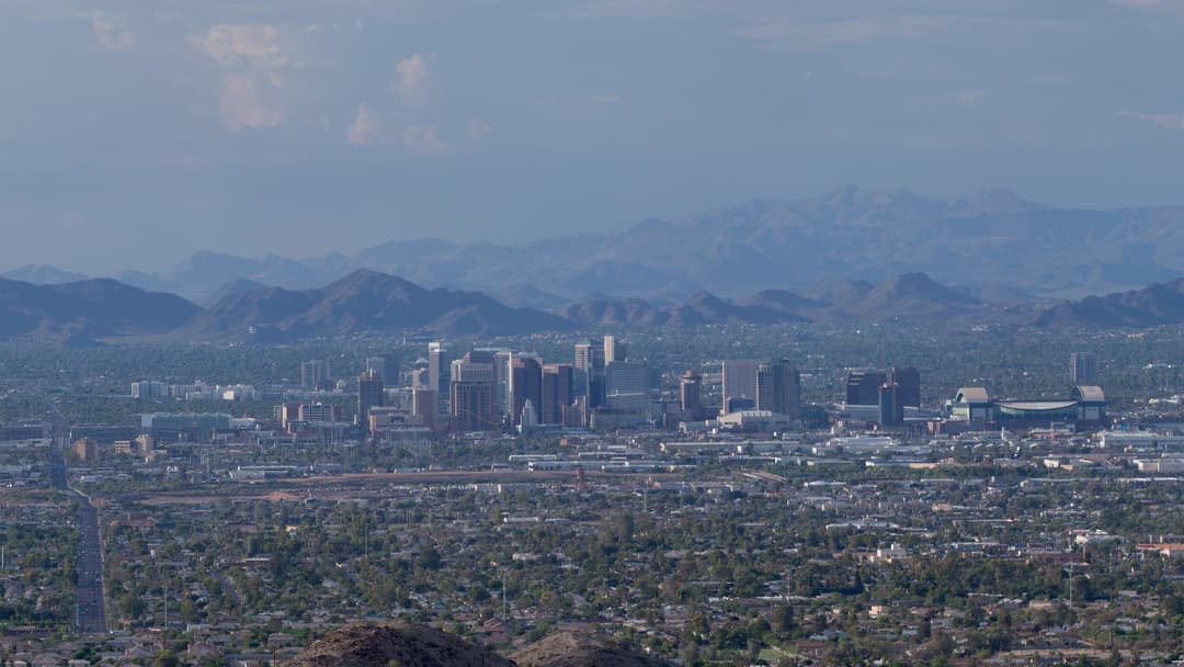 Downtown Phoenix Arizona skyline framed by desert mountains under a blue sky