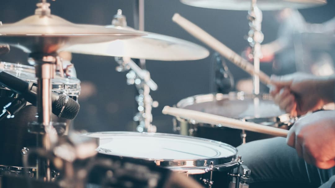 Close-up of a drummer striking a snare drum and cymbals at an energetic tempo