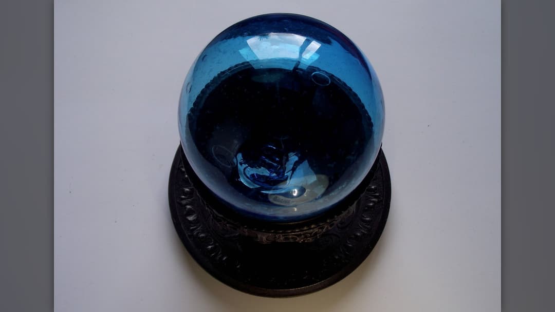Blown glass witch ball with shimmering iridescent swirls in a window