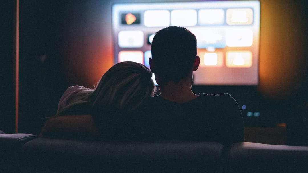Landscape photograph of a couple watching television together in a dark room