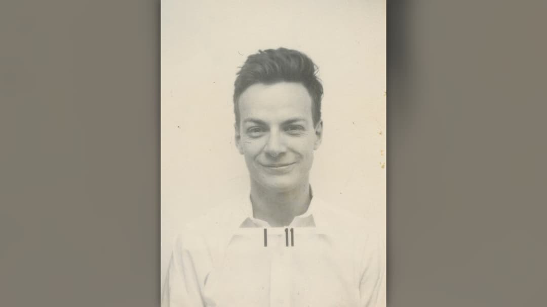 Physicist Richard Feynman smiling in front of a lecture blackboard