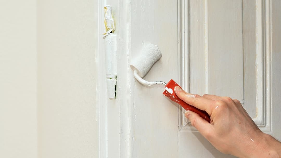 Paint roller and tray covered in white wall paint during home renovation