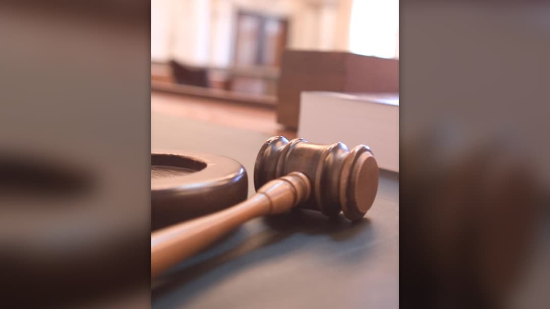 Wooden judge gavel resting on courtroom bench