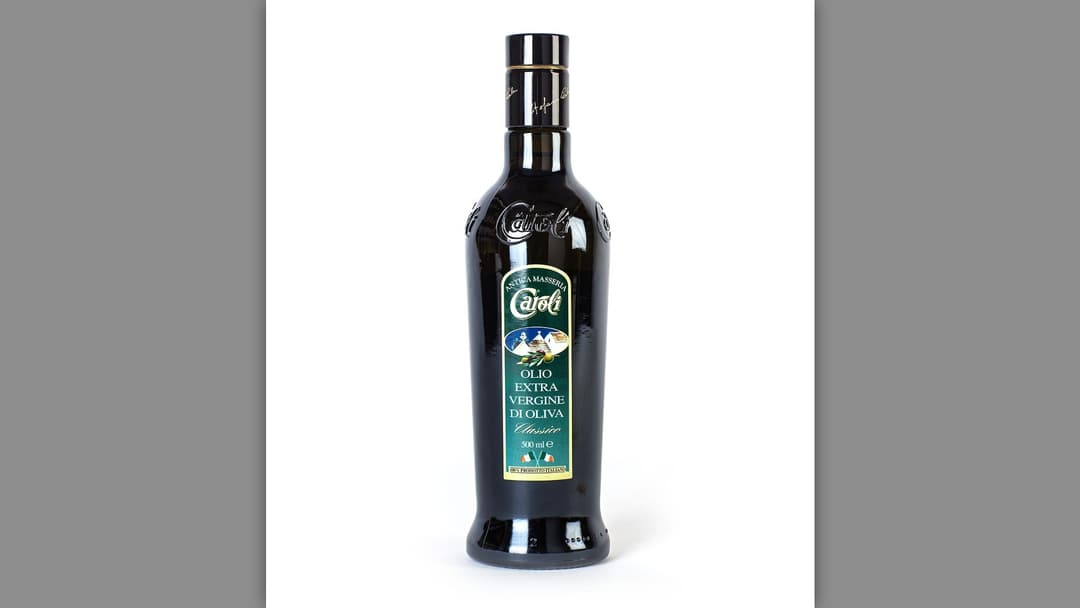Glass bottle of cold pressed extra virgin olive oil with olives