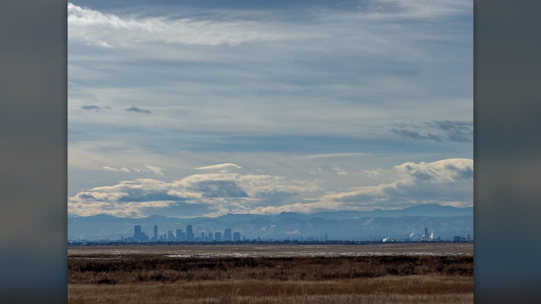 Denver Colorado downtown skyline with the snow-capped Rocky Mountains rising behind it