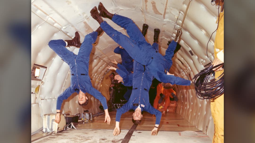 Six NASA astronaut trainees floating at different angles inside a KC-135 parabolic weightlessness aircraft