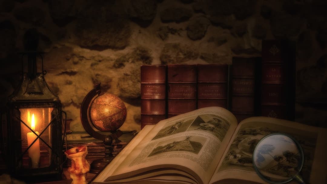 Antique leather bound book examined under a magnifying glass by lantern light