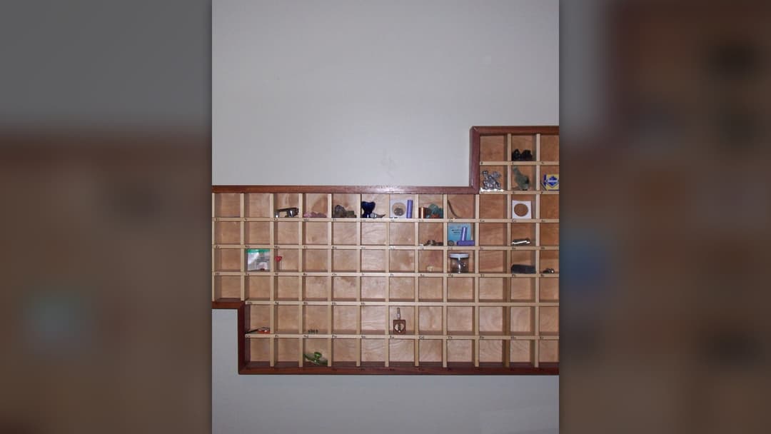 Periodic table display cabinet containing physical samples of chemical elements in labeled compartments