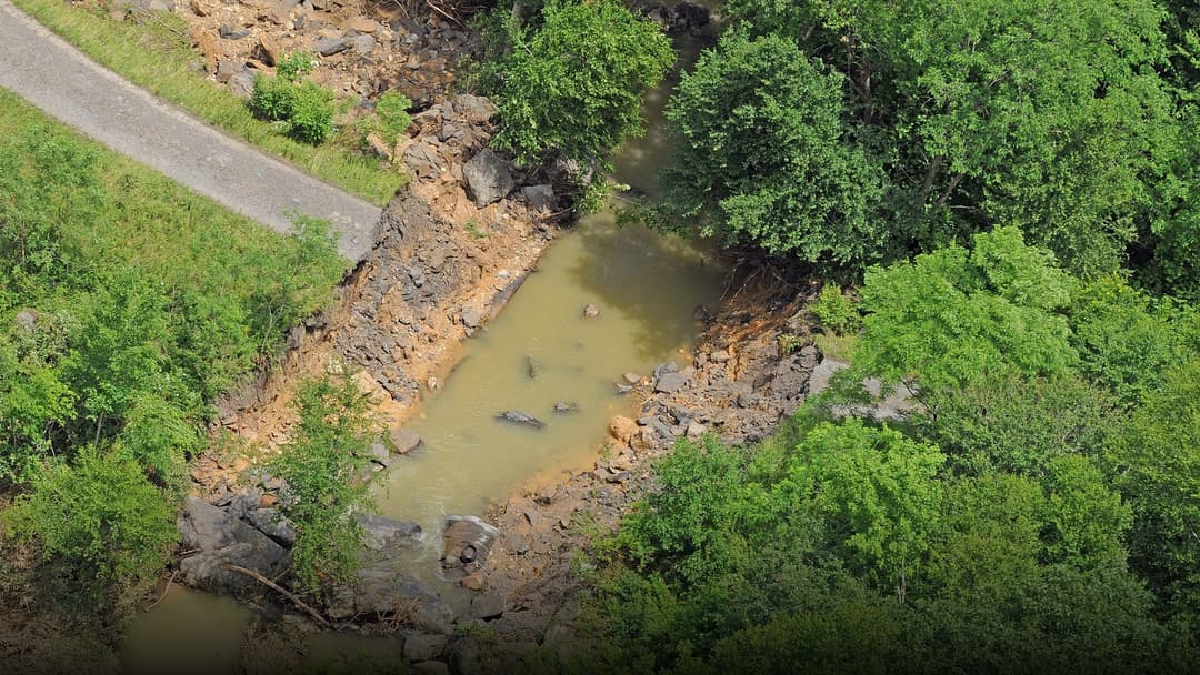 Submerged city roadway and overflowing drainage channels during heavy tropical downpours.