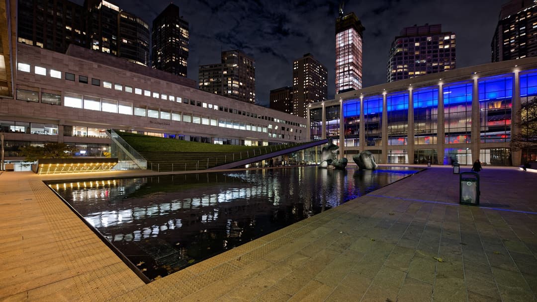 Nighttime view of The Juilliard School and the Lincoln Center reflecting pool in New York City