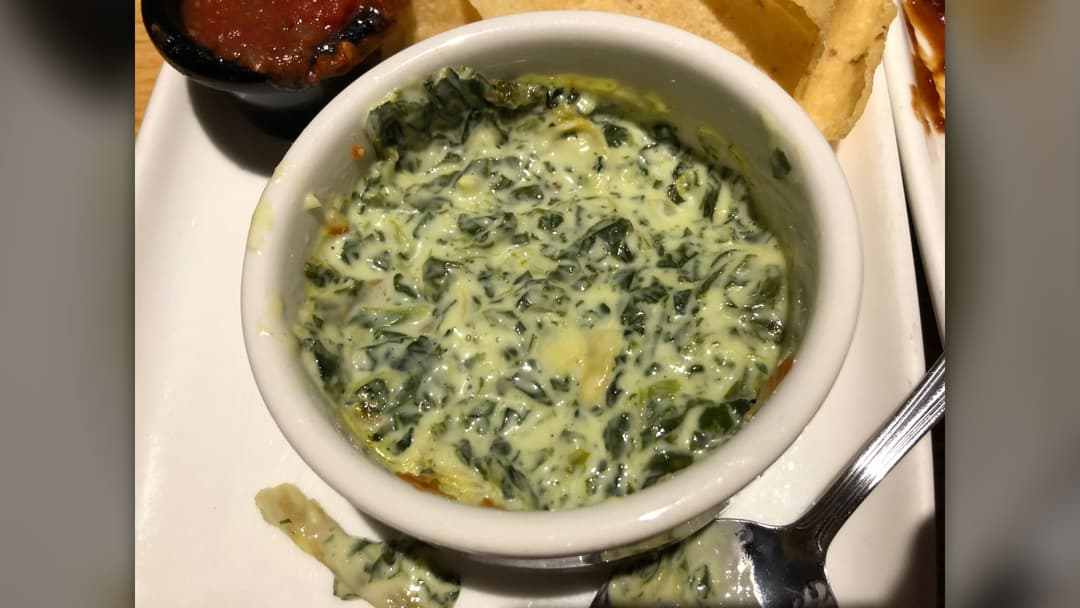 Warm creamy spinach artichoke dip served in a bowl with tortilla chips