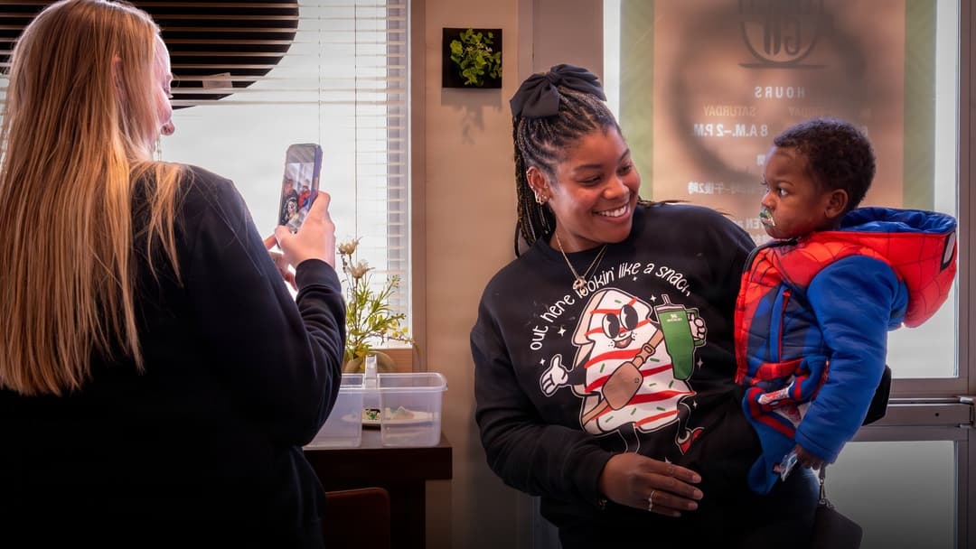 Friendly barista smiling warmly while serving a customer at the counter.