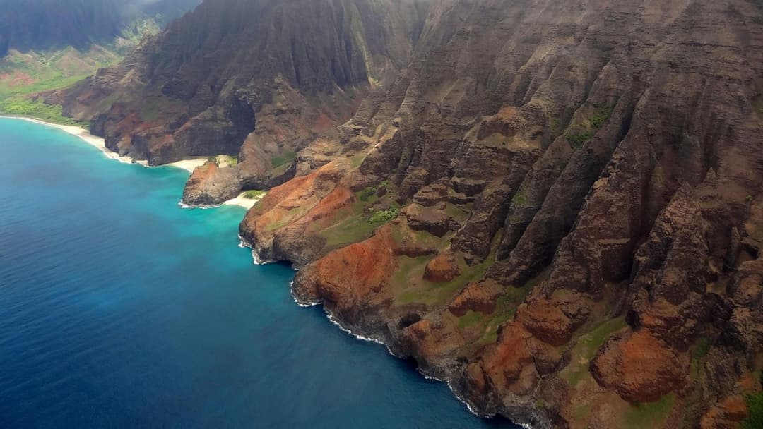 Aerial helicopter view of the lush green Kauai coastline and Pacific Ocean in Hawaii