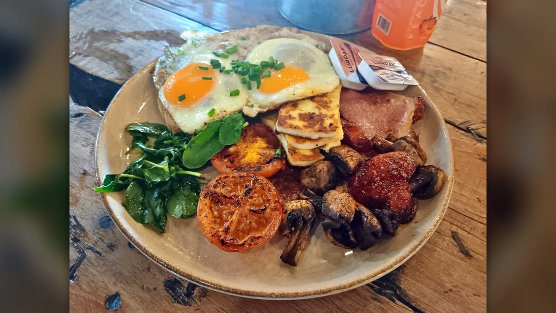 Cooked whole eggs served with baby spinach and roasted tomatoes on a breakfast plate
